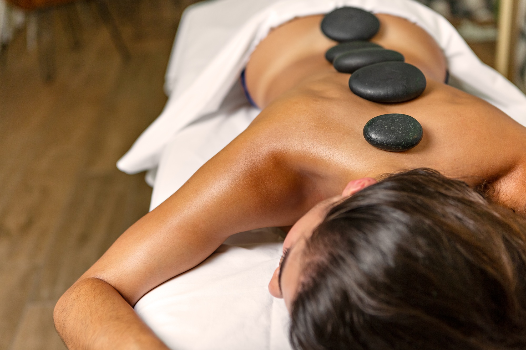 Relaxing woman with stone therapy with hot volcanic stones on back in health spa